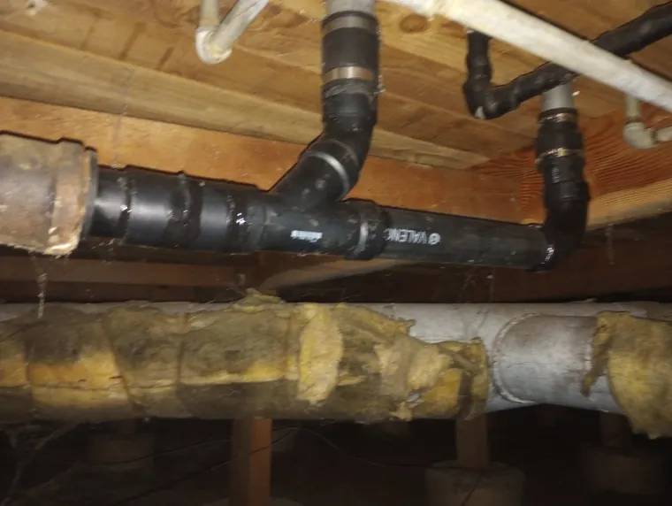 Replacement ABS drain lines installed beside failing original piping in a crawlspace in Hillsboro, Oregon