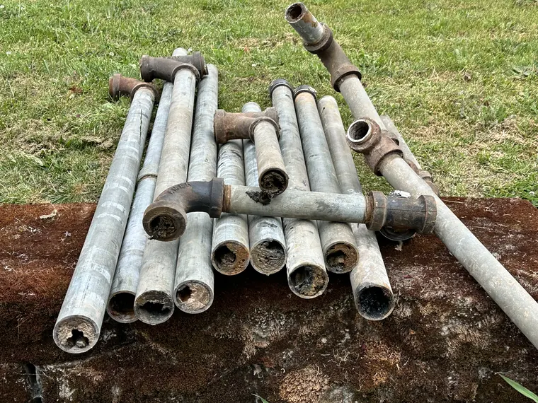 Close view of rusted galvanized water pipe sections removed during a whole home repipe in Hillsboro, Oregon