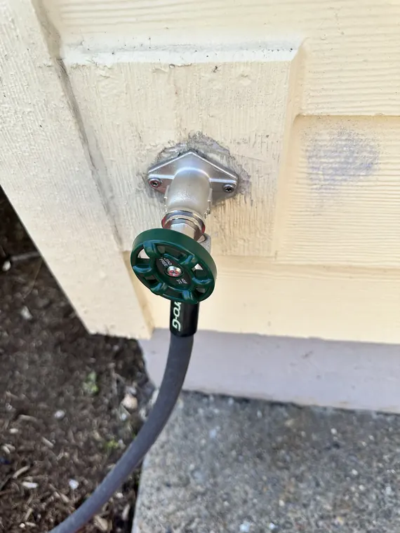 New frost-proof hose bib installed on an exterior wall with a garden hose attached in Hillsboro, Oregon