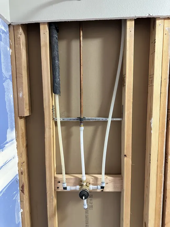 New PEX water supply lines run through open wall framing during a repipe in Hillsboro, Oregon