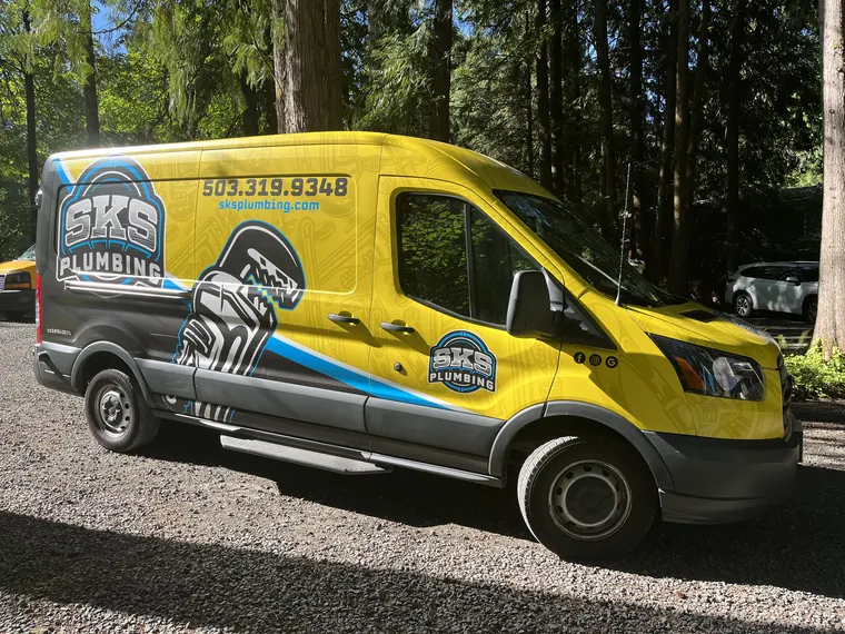 The SKS Plumbing yellow service van parked at a job site in Hillsboro, Oregon