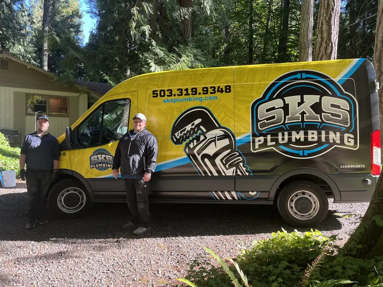 Two SKS Plumbing technicians standing beside the branded yellow service van in Hillsboro, Oregon