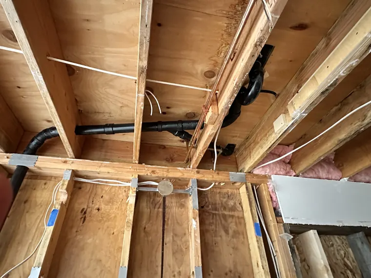 New drain lines and water supply piping roughed in under a subfloor during a remodel in Hillsboro, Oregon