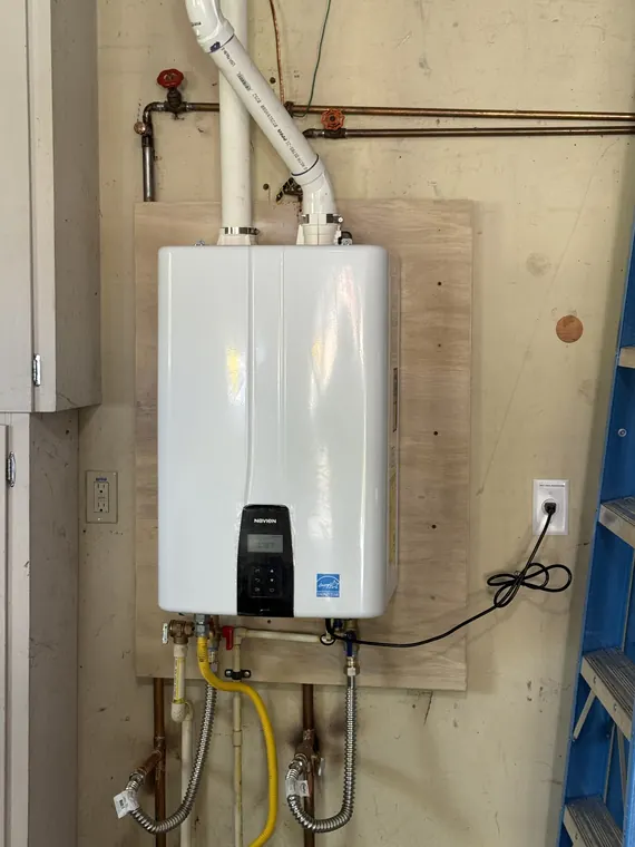 Wall-mounted tankless water heater newly installed in a garage with copper supply lines and a gas connection in Hillsboro, Oregon