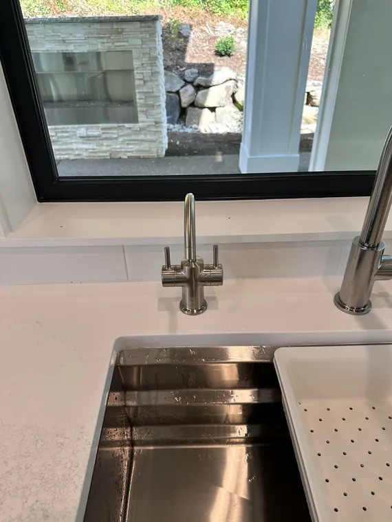 Stainless steel undermount kitchen sink with a new pull-down faucet installed beneath a window in Hillsboro, Oregon